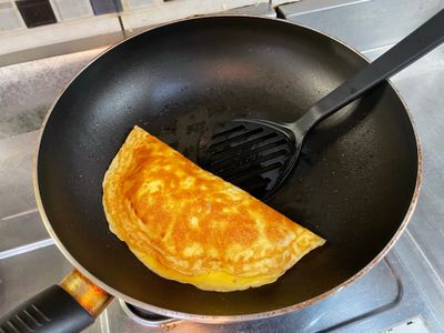 利用鍋鏟將蛋皮包起來