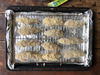 將醃好的雞柳條ㄧㄧ沾裹上麵包粉，並且靜置於烤盤中約5-10分鐘待回潮。