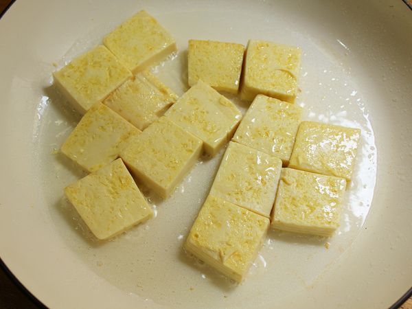取一平底煎鍋, 倒入2大匙油、豆腐平鋪, 小火煎至兩面焦香取出