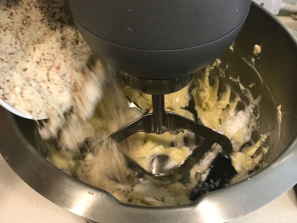持續以低速攪拌，加入鹽巴、過篩糖粉、杏仁粉、香草籽、蛋黃蛋白混合的雞蛋。