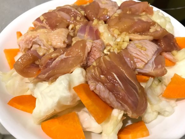 取一深盤或內鍋，先鋪上高麗菜和紅蘿蔔，放上雞肉，放進電鍋，外鍋加水1米杯後按下開關。