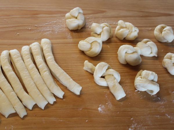 將發酵好的麵糰，桿成長條，切成約1cm寬的細條。將細條打結後兩頭接起來成一個球。