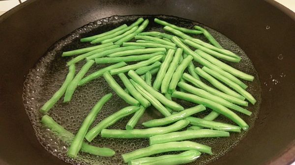 四季豆撕兩側粗夾後對切放入滾水汆燙並同時加入少許的米酒可保有四季豆的翠綠