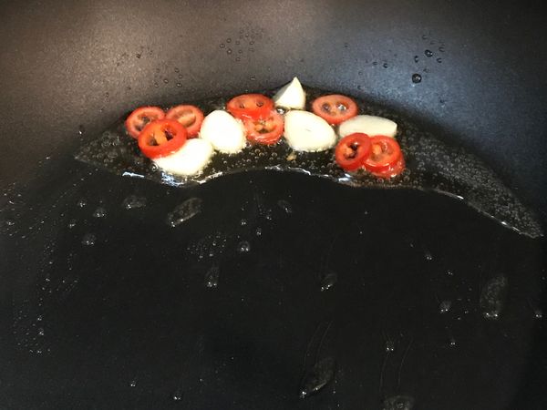 鍋中加入1大匙油加熱，放入切成薄片的蒜頭與辣椒爆香。