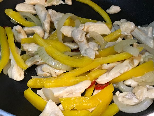 加入洋蔥炒軟後，加入雞肉略炒，再放入切成條狀的甜椒一起翻炒。