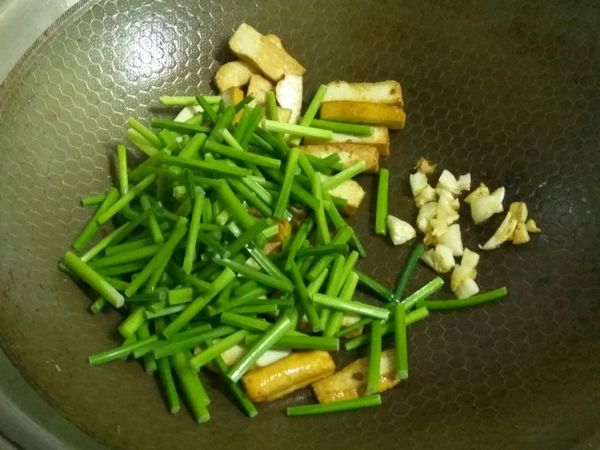 蒜頭爆香後，就可以放入靠根部的那部分韭菜，加入米酒和半杯水一起拌炒