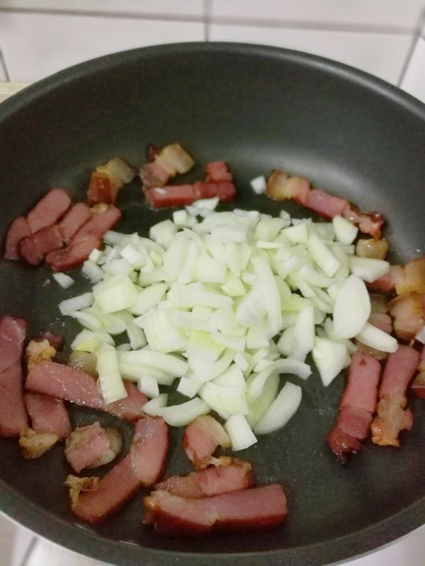 將臘肉撥至鍋邊，轉中火利用臘肉煸出的油，下1/2的蒜末、洋蔥炒至半透明，加洋菇一同炒出香味後，加2大匙煮麵水煮2分鐘。