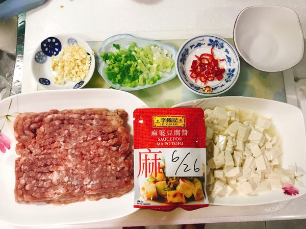 步驟一：準備材料
李錦記麻婆豆腐醬包
豬絞肉300g，如果有冷凍要先解凍唷。
佐料：大蒜切蒜末，青蔥切蔥花，辣椒切丁。
豆腐切成塊狀，把多餘的水倒掉。
另外準備勾芡水（太白粉兩匙，加兩匙水）
