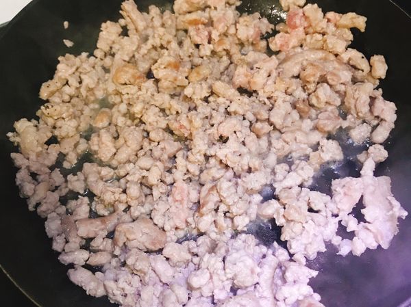 開小火，加入一匙油，將絞肉由紅翻炒至白。