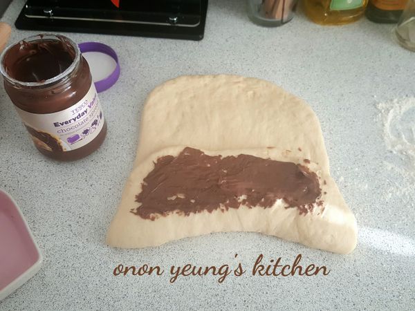 把麵糰捍成長方型後，把榛子巧克力抹醬抹在麵糰中間部分，然後下部分反摺到中間，再次抹上巧克力醬，再把上半部分往中間對摺。