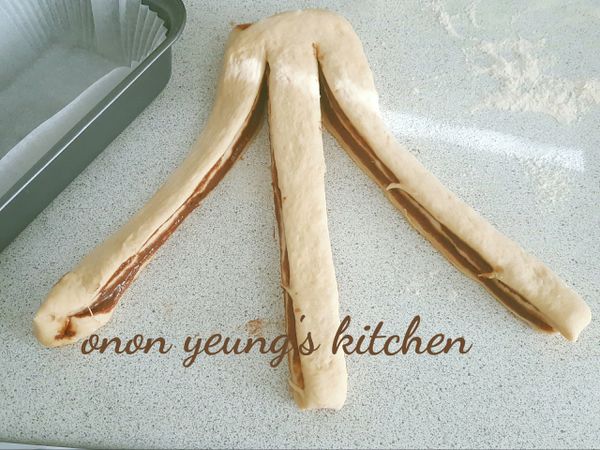 把麵糰切成3條，上方不要切斷喔！然後，交錯編成辮子形狀，放入模型中。