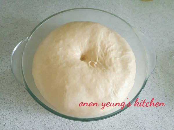 接下來進行揉麵和甩打動作，至表面光滑有韌性（注意不同品牌的粉吸水不一樣，請調節）。然後，放進底部已經搽上食用油的容器裡發酵一個小時。可以在烤箱裡放一杯熱水，把裝有麵糰（麵糰表面灑點水）的容器放進烤箱裡進行發酵過程。