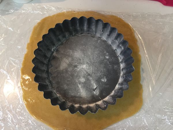 烤模抹上奶油，撒上麵粉然後前後左右搖晃烤模讓麵粉均勻附著，最後拍掉多餘麵粉。取出塔皮，上面再鋪上一層保鮮膜然後桿平到超過塔模。撕掉上層的保險膜，將塔皮反鋪進烤模，隔著保鮮膜把皮輕壓進塔模裡。輕撥去上方多餘塔皮。整型好就放冷藏