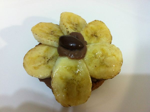 香蕉排列成花的形狀，中心擠上些許巧克力風味卡士達醬，再放上一顆杏仁巧克力豆。