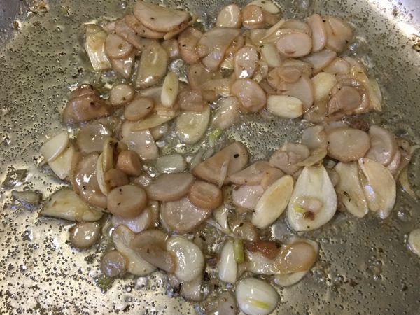 用鍋內的雞油將蒜片、香菇頭爆香。