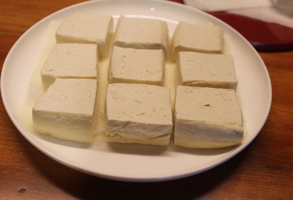 壓好的豆腐，紙巾上吸滿了水分，豆腐變的較為結實有彈性。先分切成小塊比將一大塊豆腐去壓更容易壓出水分和保持形狀。