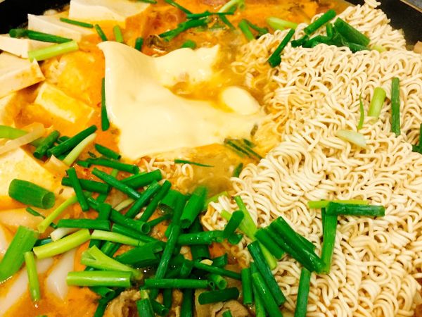 陸續放入年糕、百頁豆腐、德式香腸、王子麵，最後放上起司片及蔥段即完成