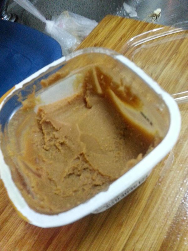 放入水,蒜頭,魚丸,油豆腐,板豆腐,豆腐用手剝成小塊,加入一半的味噌煮滾後小火續煮一下