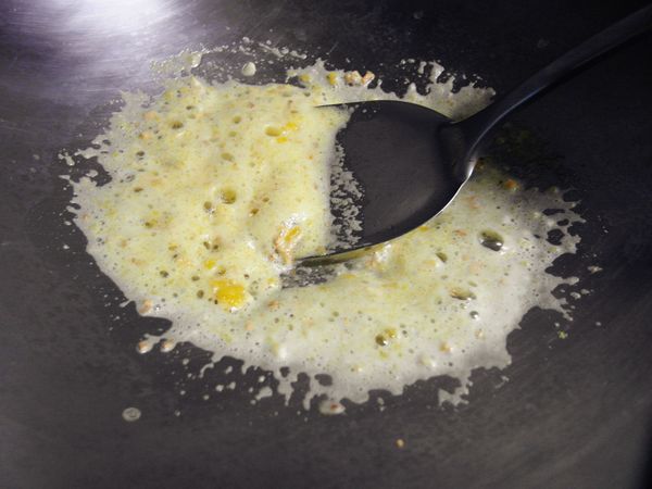 倒油爆香蒜頭之後，倒入蛋黃用鍋鏟壓扁，炒出泡沫