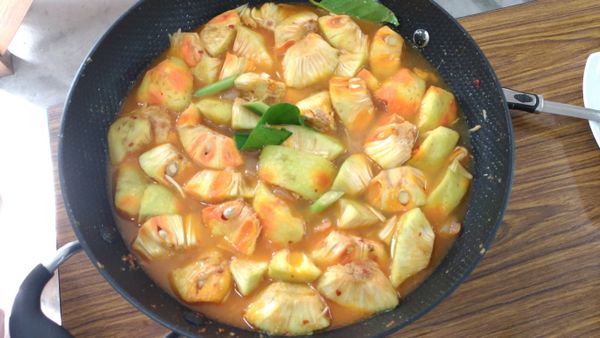 加入咖哩醬，加入麵包果拌炒與調味料香茅、檸檬葉。