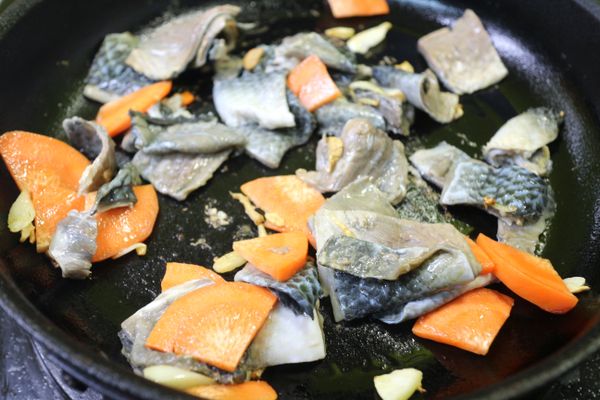 再下虱目魚皮入鍋內,過程中倒入一大匙米酒和魚皮拌炒,可以去除腥味
