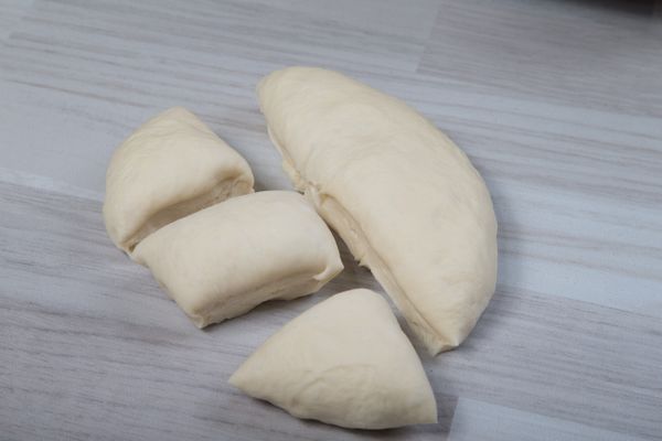 將麵糰進行分割成約60g，約可均分成13-14顆，稍微滾圓(避免麵糰過緊)，將麵糰放在烤盤上鬆弛10分鐘。