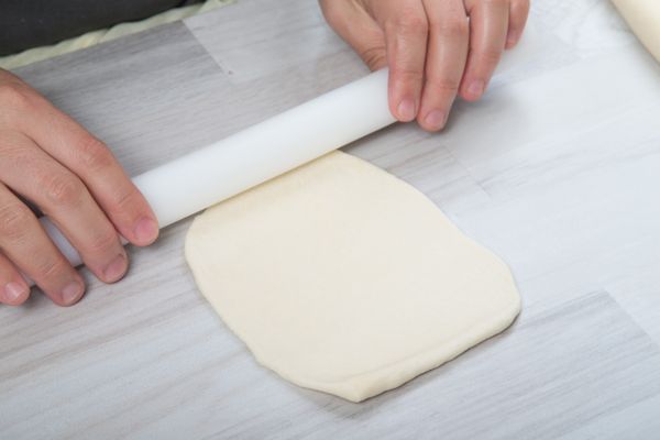 使用擀麵棍將麵糰擀平成長方型片狀。
