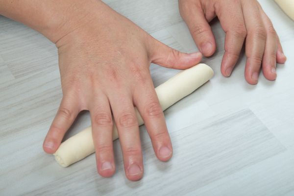 將麵糰以一指幅寬度向下捲起成緊實長棒狀，搓長為約20cm
，麵團收口接縫朝上。