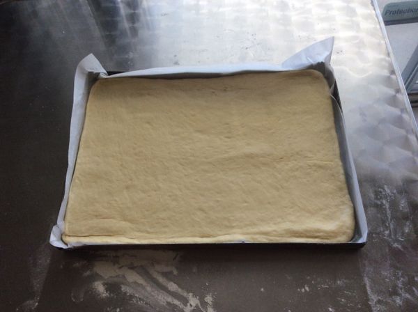 把麵片放入烤盤中，並儘量整形與烤盤一致。麵片放入時可兩面抹些高粉，再用擀麵棍捲起放入烤盤。烤盤尺寸是26X36公分的長方烤盤。再次發酵至兩倍大。