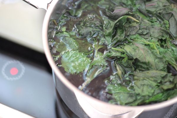 清水煮滾加入赤紫蘇葉跟著煮，葉片中水溶性的花清素漸漸融入熱水裡，葉子從紫黑色轉成綠色。