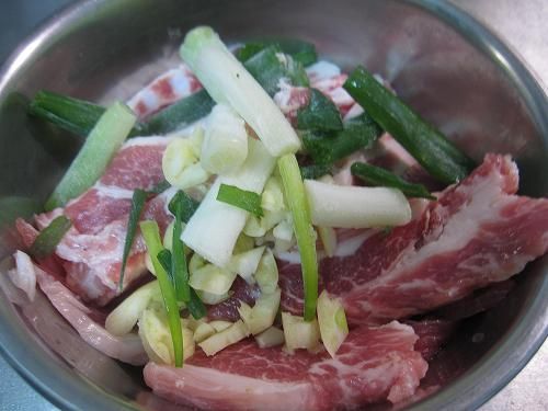 豬肉切成薄片、蒜頭拍成碎粒、蔥切成中長段後，全部放置小盆中備用。