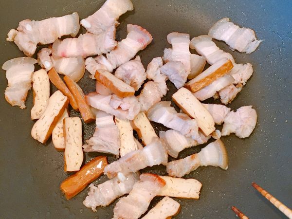 五花肉逼出油後，放入豆乾，炒至焦香