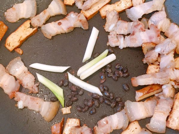 鍋裡的油爆炒蔥段、辣椒及豆鼓，鍋邊嗆入少許米酒，再下醬油及糖調味