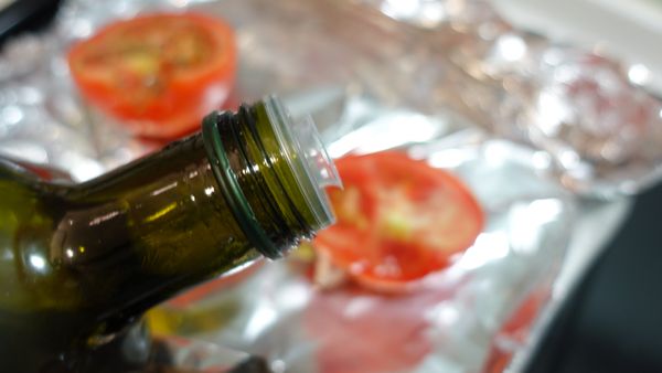 烤盤上鋪上錫箔紙，將切半的牛蕃茄剖面淋上冷壓初榨橄欖油。