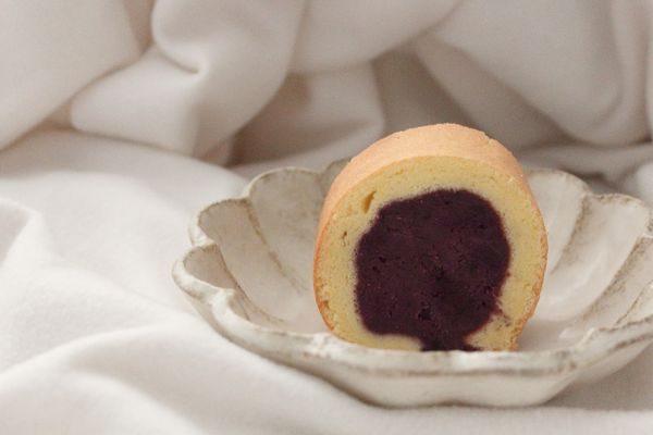 放涼後翻到背面將烤紙撕開，在把適量的紫薯泥放到蛋糕捲上抹平
靠近自己的那邊疊較多上紫薯
在連著烤紙藝起捲起
放冰箱定型1小時就可以切片囉!