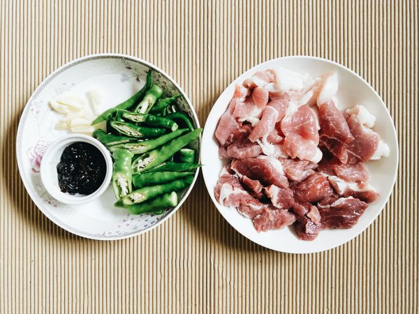 將五花肉切片約0.3公分的厚度。糯米椒洗淨切段。蒜切片。以上材料洗切好備用。