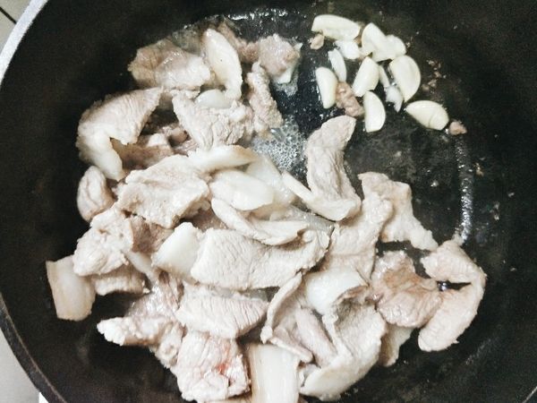 將肉片放入煎至略帶金黃。接著放入蒜片爆香。