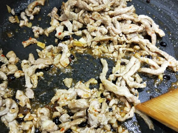 肉絲炒香炒熟後，倒入剛拌勻的調味料一起拌炒至收汁