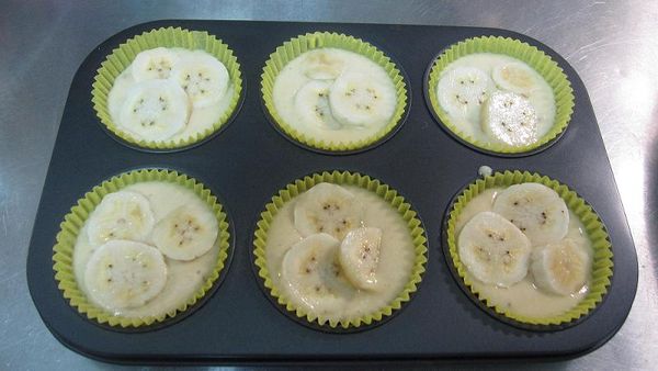 把拌好的麵糊倒入烤盤中，上面放上切片的香蕉片裝飾。