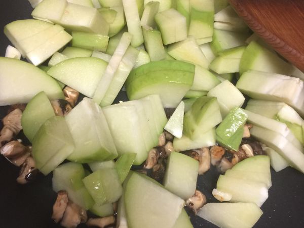 香菇泡水後擠乾切丁，香菇水留著備用，佛手瓜洗淨後切塊，蒜頭切碎末。開火加少許油，放入蒜頭和香菇炒個半分鐘，放入佛手瓜拌炒，加入香菇水。