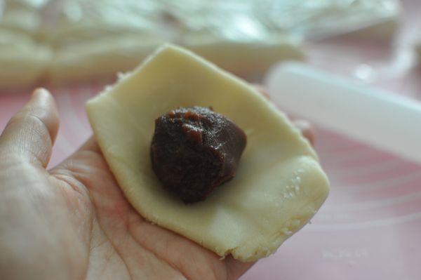 将静置好的皮擀开，将裹好豆沙的咸蛋黄包住，封口一定要捏紧，