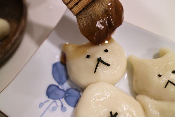 用海苔剪成眼睛、鼻子和嘴巴的形狀放到頭部，剪數個細長條海苔作一個米字形圖案來呈現屁股的模樣，將煮好的日式甜醬油用刷子刷在小柴的頭部和身體的地方