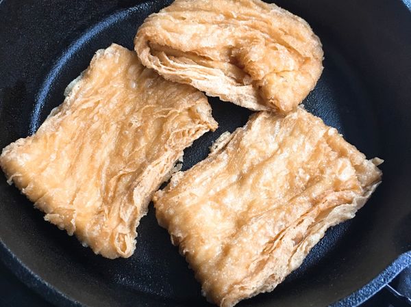 鍋中倒少許油，放入豆包，煎到表面稍微變色酥香，取出切塊（1片切成4塊）