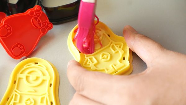 在掃子上噴上油後，在曲奇模上仔細掃上薄薄的一層油。