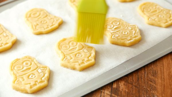 把曲奇放到己鋪上烘焙紙的烤盤上，用掃子輕輕掃走曲奇上多餘的麵粉。