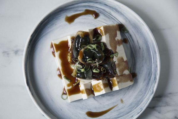 取一個略深的盤子，將豆腐扣入其中，先橫切一半後再直切四刀，放上皮蛋。淋上醬汁、撒上蔥花即可享用。