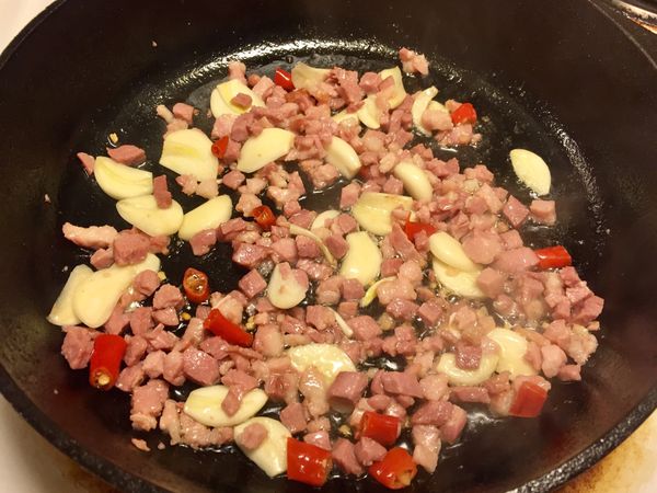 平底鍋加入橄欖油加熱後，放入培根丁。
培根炒香再加入蒜片、切段辣椒拌炒，培根丁呈焦香色。