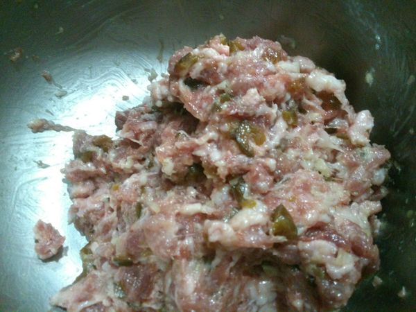 將蒜末和花瓜丁與絞肉攪拌均勻。