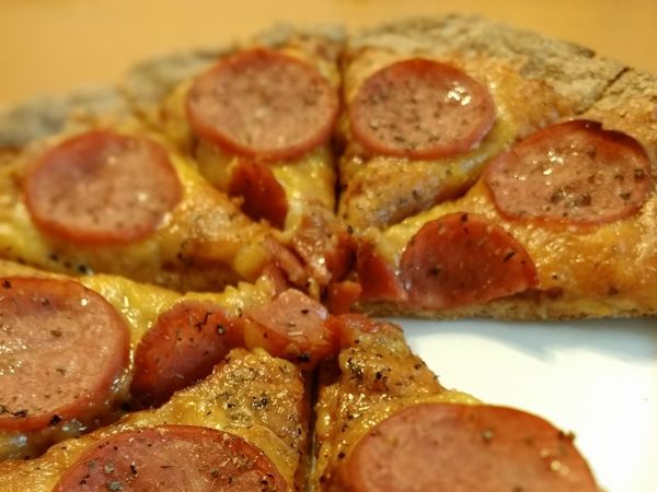 取出後，將餅皮翻面，原本底部變正面。塗上披薩醬，放上大量起司，再披上火腿片，撒上蘿勒葉及黑糊椒，上下火250，送入烤箱，烤15分即可。