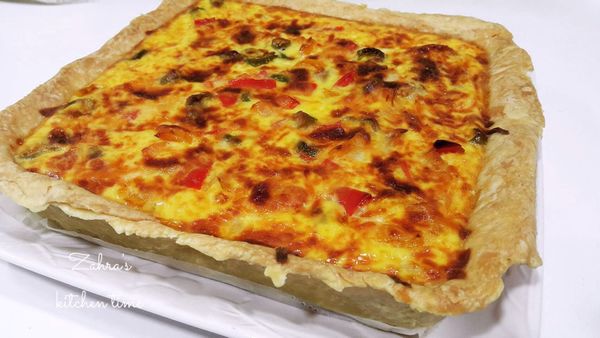 依序將炒熟的洋蔥絲和洋菇放入派皮底部>放入雞腿丁>放入紅黃甜椒和青椒，倒入蛋液約派盤的8分滿，最後均勻撒上披薩起司，放入烤箱內，烤溫200˚C，大約烤25 - 30分鐘，或是表面已上色就完成了。